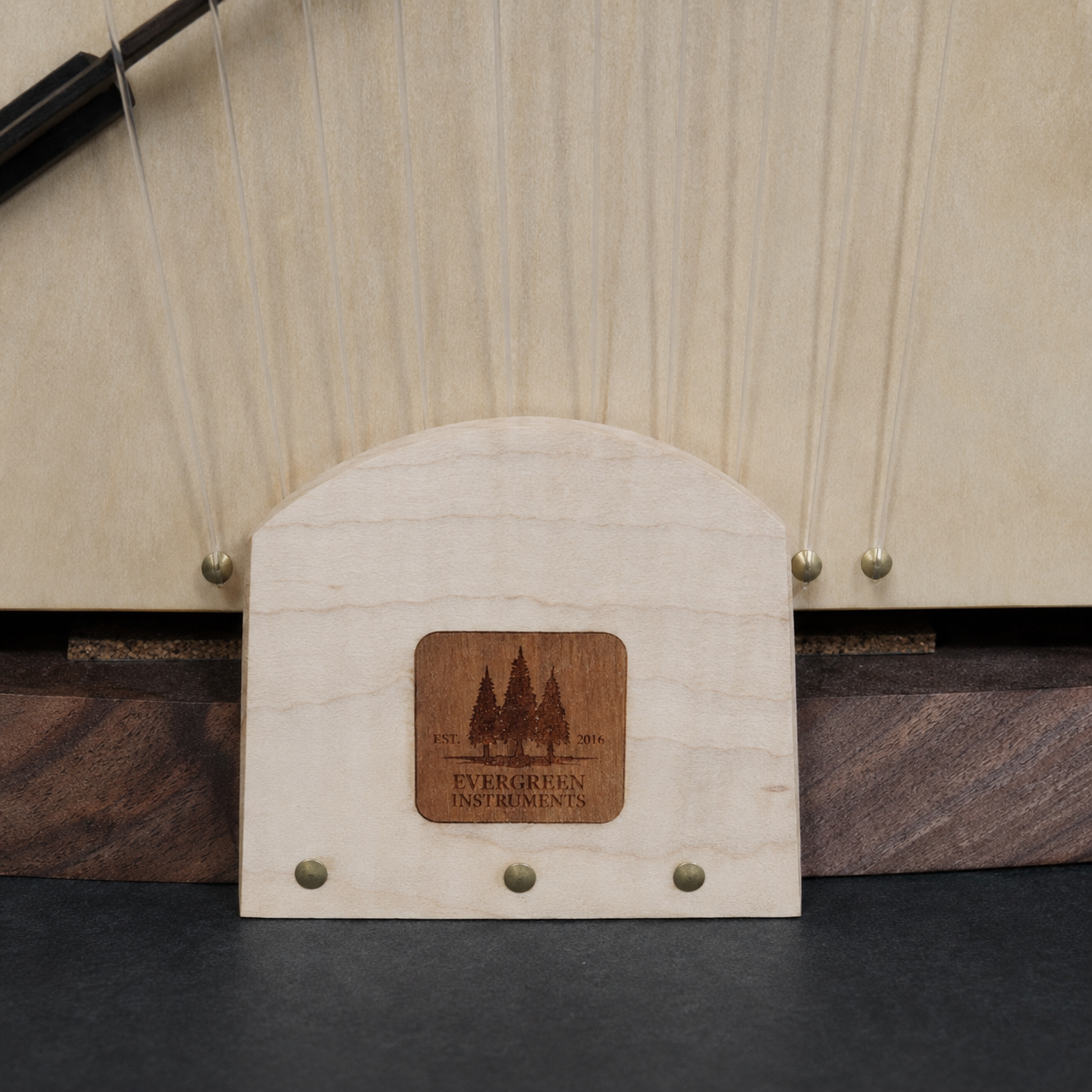 Close-up of the matching handmade wood stand with Evergreen Instruments logo